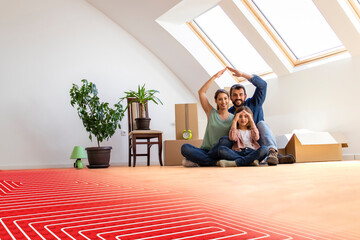 Floor heating concept - portrait of happy family sitting on warm parquet with floor heating and...