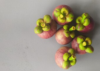 Bunch of isolated organic farm fresh purple fruit mangosteen also known as garcinia mangostana and mangostan stacked on wet white background with water drops and copy space. Fruits close up top view. - obrazy, fototapety, plakaty