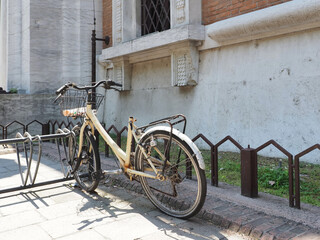 Fototapeta na wymiar Ferrara, Italy. An old bicycle without a saddle abandoned in the bicycle rack of the Central Post Office.