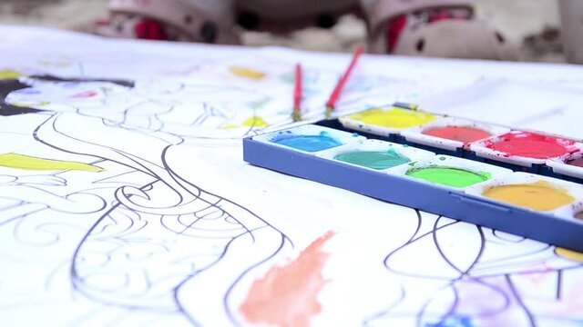 The child draws with paints. Children's concept. The little girl paints with colored paints. Children's drawing. Children Protection Day. Children's hand draws with paints close-up.