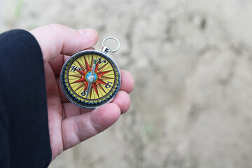 Old classic navigation compass in hand on natural background as symbol of tourism with compass,...