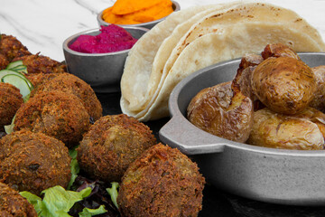 Indian vegetarian cuisine. Closeup view of vegan fried kibbehs, beets and carrot hummus, and corn tortillas on the table.