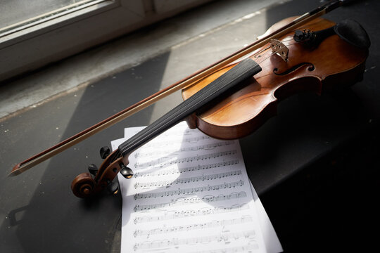 Violin placed on windowsill near sheet music