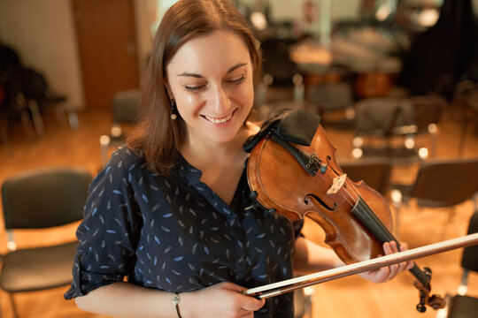 Happy female violinist performing classical music in hall