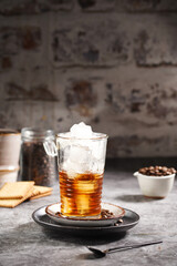 a glass with ice cubes filled with brown liquid coffee halfway