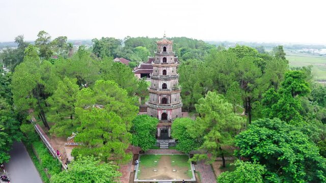 Aerial Tilt Down Shot Of Tourists At Thien Mu Pagoda Against Sky, Drone Descending Over Popular Landmark Amidst Green Trees - Hue, Vietnam