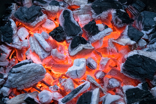 Closeup of glowing and flaming pieces of coal. Ready to start a barbecue. © silentstock639