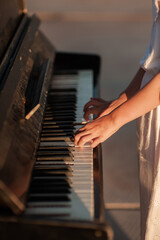 Female hands press the keys on the piano. Outside
