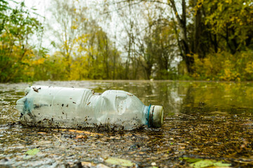 Una bottiglia di plastica trasportata dall'acqua dopo una ondata di piena. - obrazy, fototapety, plakaty