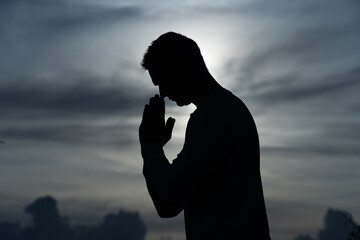 Silhouette of Man pray on during sunset. Religion, faith and hope concept 