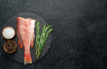 Raw red sea bass fish on stone background with spices on a stone background
