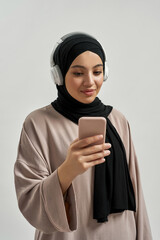 Young arabian girl in headphones holding smartphone