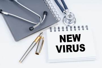On the table are a stethoscope, a pen and a notebook with the inscription - NEW VIRUS