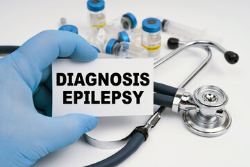 There is a stethoscope on the table, the doctor is holding a business card with the inscription -...
