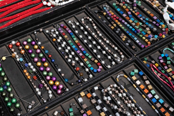 Colorful cheap jewelry at a market stall with a black background