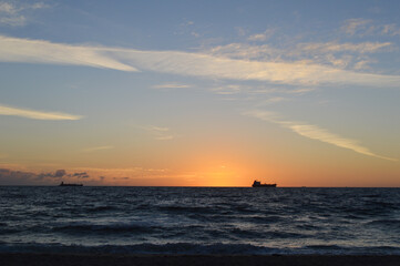 Fototapeta na wymiar Beautiful Sunrise on Fort Lauderdale Beach, Florida, USA with fishing boat far away