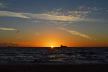 Beautiful Sunrise over the ocean line on Fort Lauderdale Beach with fishing boat far away