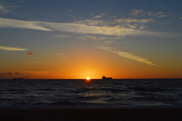 Beautiful Sunrise over the ocean line on Fort Lauderdale Beach with fishing boat far away