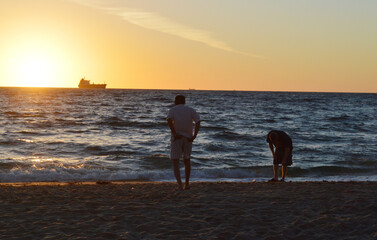 Local men walking on the shore of Fort Lauderdale beach, Florida during beautiful sunrise