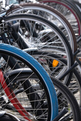 Fototapeta na wymiar Detail of the wheels of parked bicycles in Maastricht, Netherlands. Focus on the blue bicycle tire in front. Vertical photo with selective focus. Dutch bicycle parking. City biking