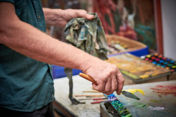 Artist mixing paint with a palette knife in art studio