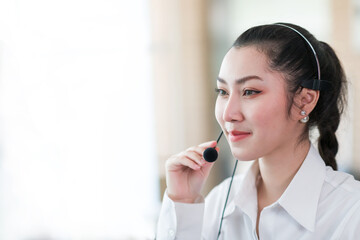 Asian call center woman worker at work. Smiling female customer support operator with headset working in the office. Contact center and customer service by headphone concept