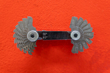 Thread pitch gauge or Screw pitch gauge on orange background.