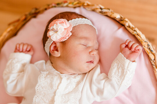 Cute sleeping baby girl in smart white dress and golfs lies on a round crib. photo shoot of newborns