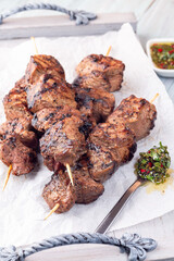 Beef meat skewers with chimichurri sauce, on wooden tray, vertical