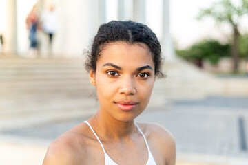 Headshot of a yong serious African american woman looking in to the camera outdoors