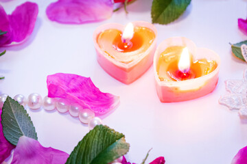 Romantic background. On a white sheet rose petals, decorations and candles.