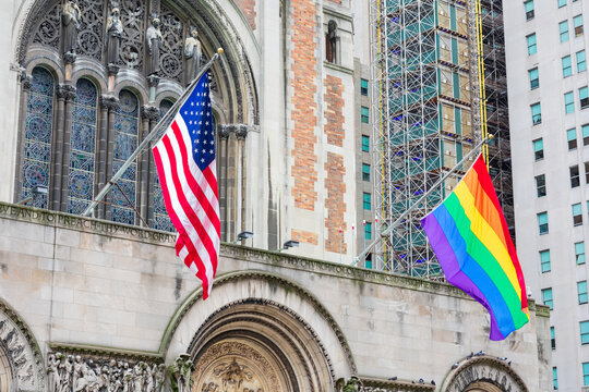 Flag of the United States, Rainbow Pride Flag flying waving on the facade of St. Bartholomew's Church. - New York, USA - June 2021