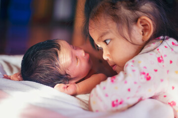 The sister lay staring at her brother who was a week old with love