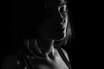 Portrait of attractive a young woman with cinematic lighting. Dramatic monochrome, black and white photo. Woman wearing a suspender bodysuit. Half naked sexy woman. Horizontal shot.