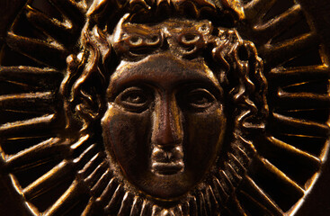 Metal greek male face bronze relief close up photo.