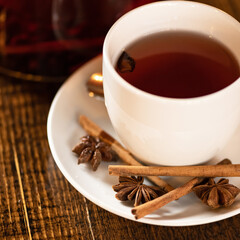 Cup of black tea with anise and cinnamon spices. Close up shot. Square format. Selective Focus on foreground.