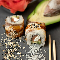 Inside-out Sushi roll with eel decorated with sesame seeds. Sushi Set. Classic Japanese food. Oriental cuisine. Close up shot. Soft focus.