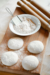 Cooks roll dough for baking, pieces of raw dough on wooden Board