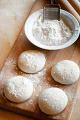 Cooks roll dough for baking, pieces of raw dough on wooden Board