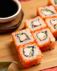 Sushi rolls decorated with sesame seeds and masago or tobiko caviar. Inside-out Sushi Set. Different types of rolls. Asian or Japanese food, Oriental cuisine. Close up shot. Top view. Soft focus.