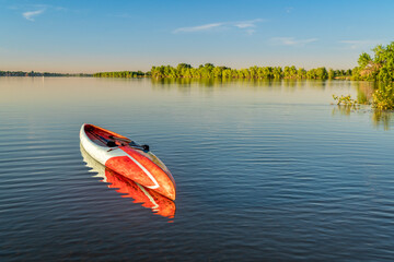 stand up paddleboard is floating on a calm lake - Boyd Lake State Park in northern Colorado,...