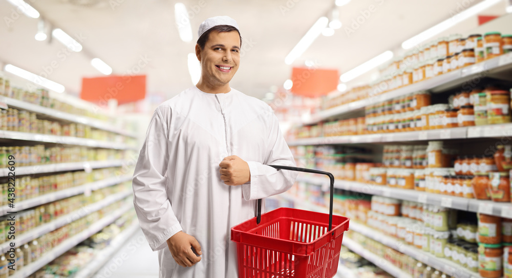 Wall mural young man in ethnic clothes holding a shopping basket