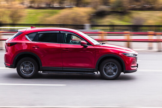 Woman Is Driving Red Mazda CX-5 On The Street. SUV Car In Motion On The City Road. Compliance With Speed Limits On Road Concept.