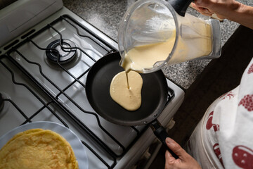 Woman cook preparing pancakes in a frying pan