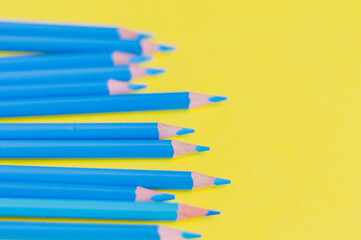 Sharpened blue pencils on a yellow background.