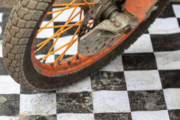 The wheel of the motorcycle is sporty for cross and motorcycle freestyle, racing against the background of white and black background cells. The concept of professional motorsport. Copyspace