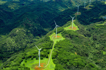 Aerial photo of white windmills in a line on green land leading off into the horizon.