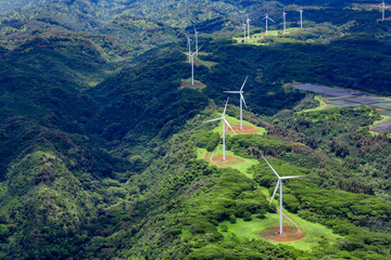 Aerial photo of white windmills in a line on green land leading off into the horizon.
