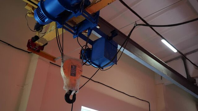 Hook wrapped with plastic foil on long metal bar in brightly lit spacious workshop at production plant close view