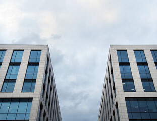 cloudy sky between the corners of two tall modern office buildings with dark glass windows